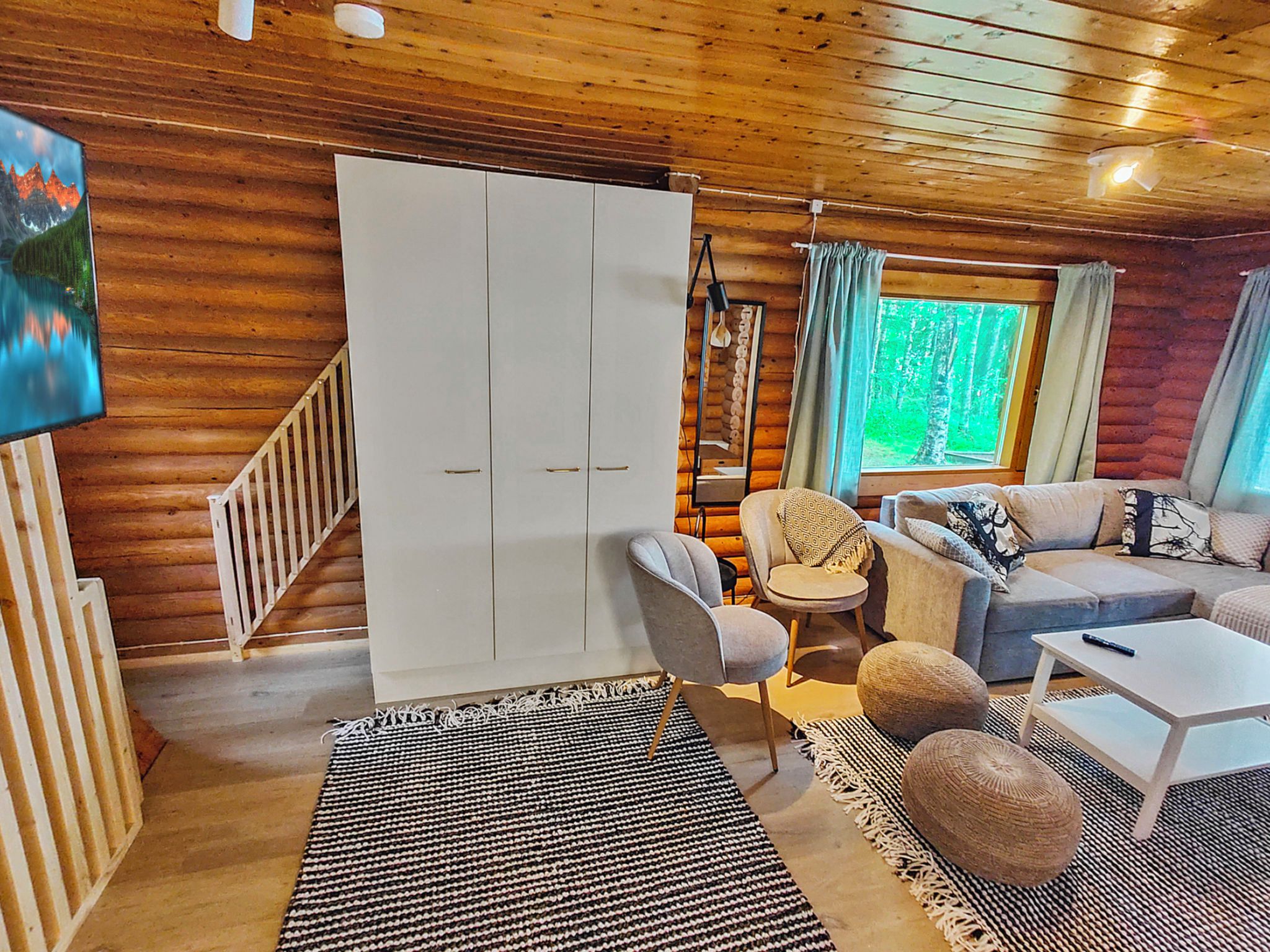 A cozy cabin interior with a sofa, armchair, and a large wardrobe.