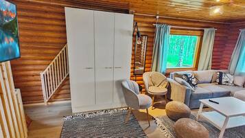 A cozy cabin interior with a sofa, armchair, and a large wardrobe.