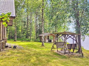 A cabin with a porch and a swing chair, surrounded by a forest and a lake. - Koivula by Interhome (Soini)