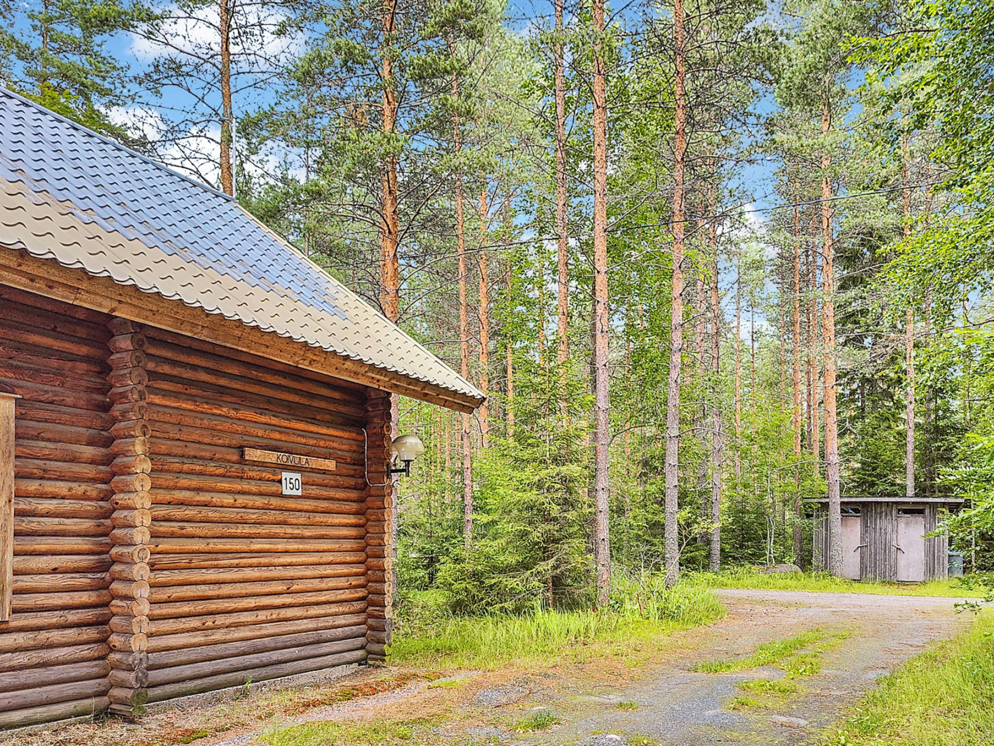 Puinen mökki, jonka katto on tehty metallista, ja jonka ympärillä on metsä.