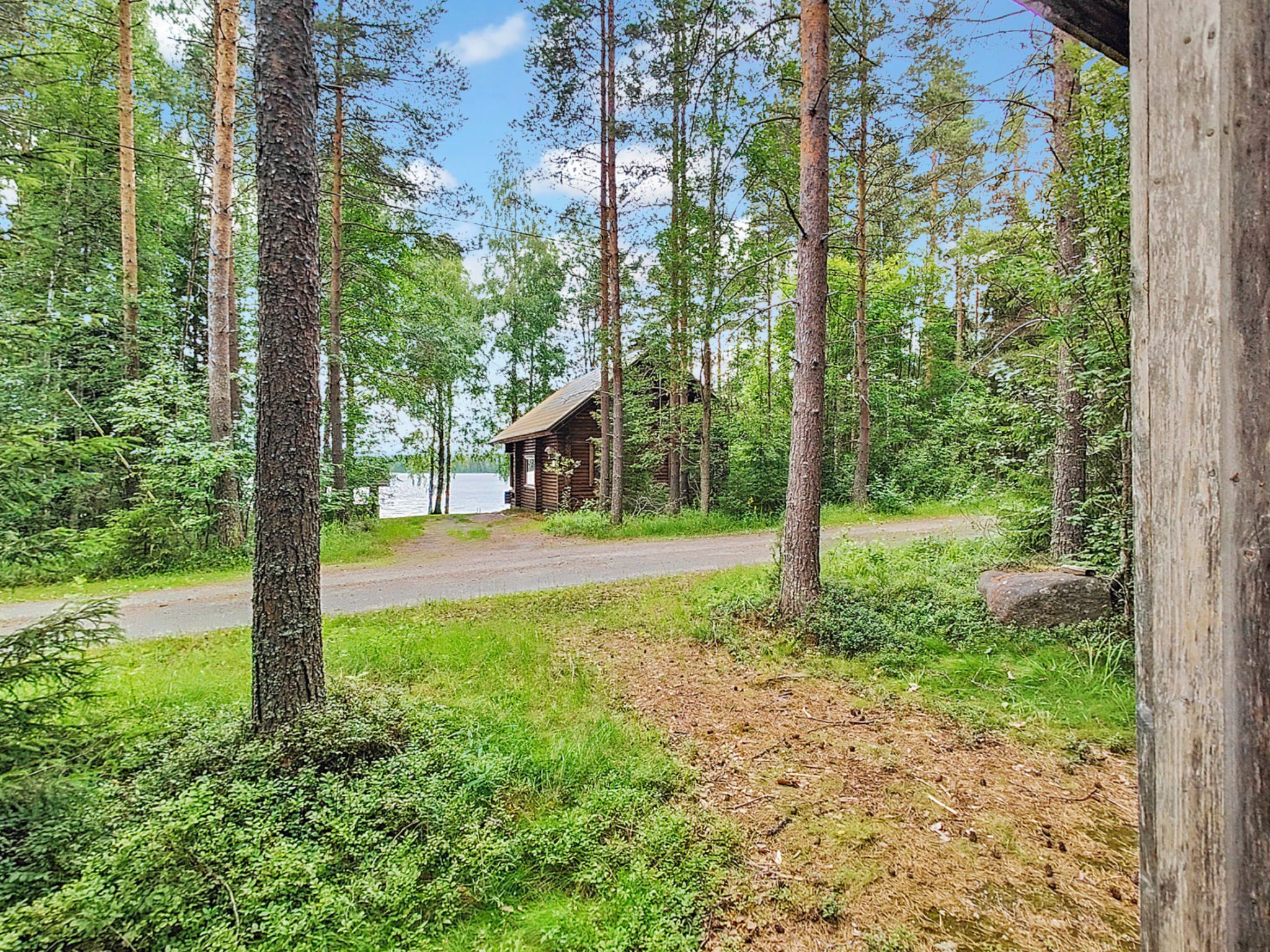 A cabin surrounded by tall trees and a clear sky.