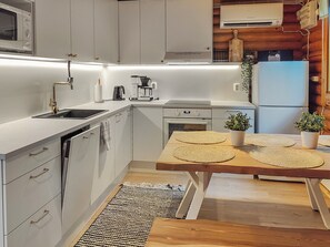 Een moderne keuken met witte kastjes, een ingebouwde oven, een koffieapparaat en een eethoek met een houten tafel en placematen.