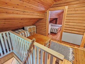 A wooden cabin with a loft bedroom, a dining area, and a staircase.