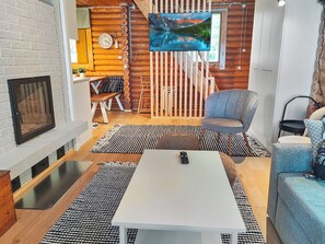 Una sala de estar moderna con chimenea, un televisor de pantalla plana en la pared y un rincón de descanso acogedor con sofá y sillón.