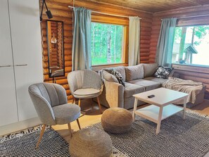 Een vakantiehuisje met een bank, stoelen, een tafeltje en een rond poef.