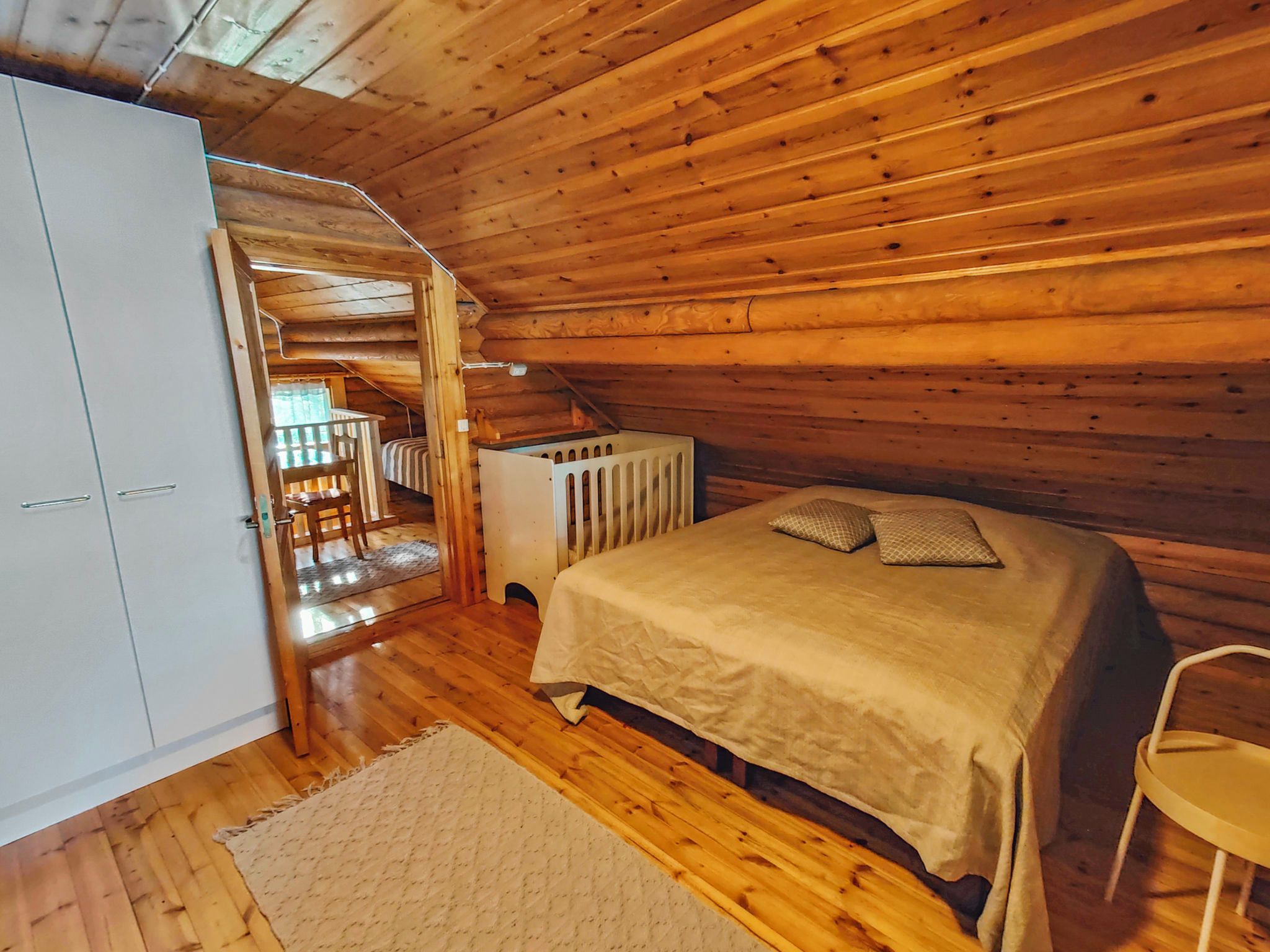 A bedroom with a bed, a radiator, a chair, and a wardrobe.