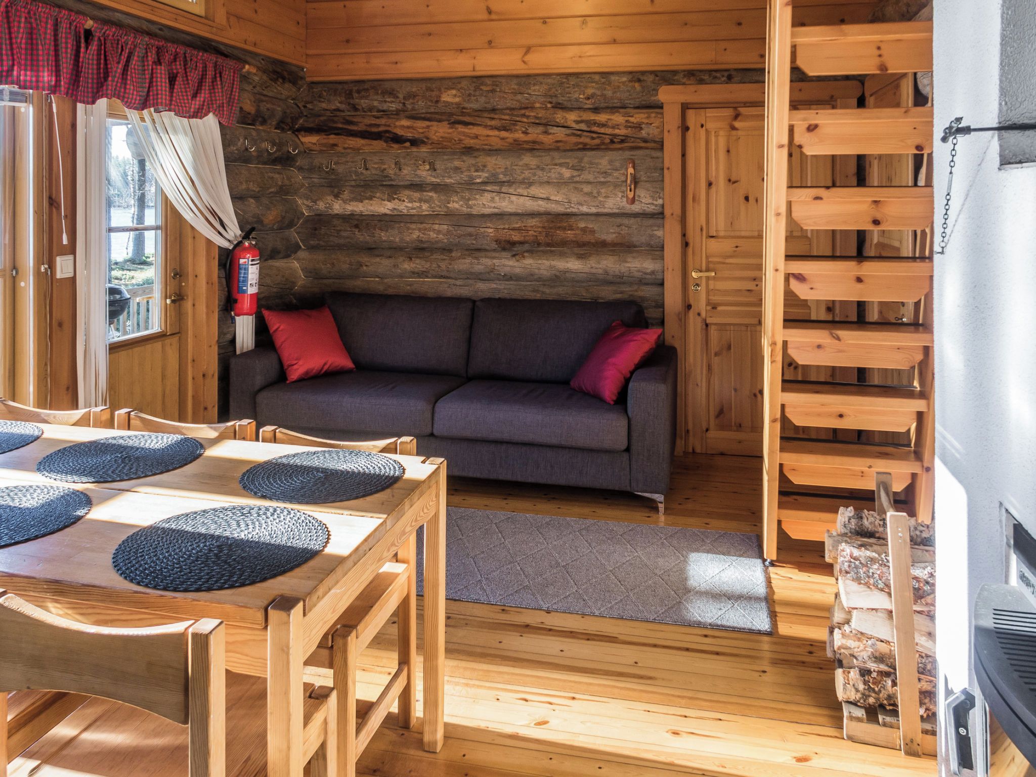 Interior acogedor de una cabaña con una mesa de comedor de madera, un sofá y una chimenea.
