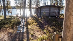 Järven rannalla sijaitseva puinen mökki, jolle johtaa kivistä rakennettu polku.