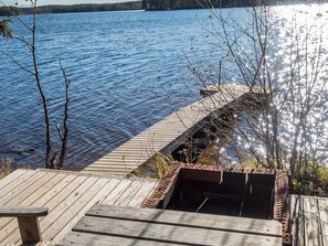 A wooden dock extending into a calm lake with a forest in the background.