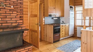 A compact kitchen with wooden cabinets, a brick wall, a built-in oven, and a microwave. - Vacation home 2234 by Interhome (Savonlinna)