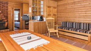 A wooden interior with a dining table, a sofa, a chair, and a kitchen area. - Vacation home 2234 by Interhome (Savonlinna)
