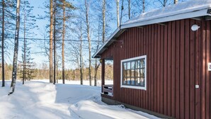 A wooden cabin with a window and a door, surrounded by snow-covered ground and trees. - Vacation home 2234 by Interhome (Savonlinna)