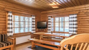 A cabin interior with wooden walls, a wooden bench, a TV, and a window with a view of trees. - Vacation home 2234 by Interhome (Savonlinna)