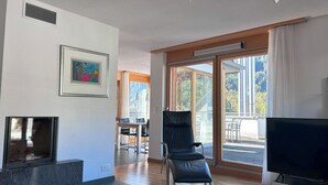 Un saló modern amb una llar de foc, una televisió i una zona de menjador amb llum natural.