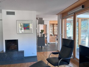 Una sala moderna con chimenea, una obra de arte enmarcada y vista a la cocina.