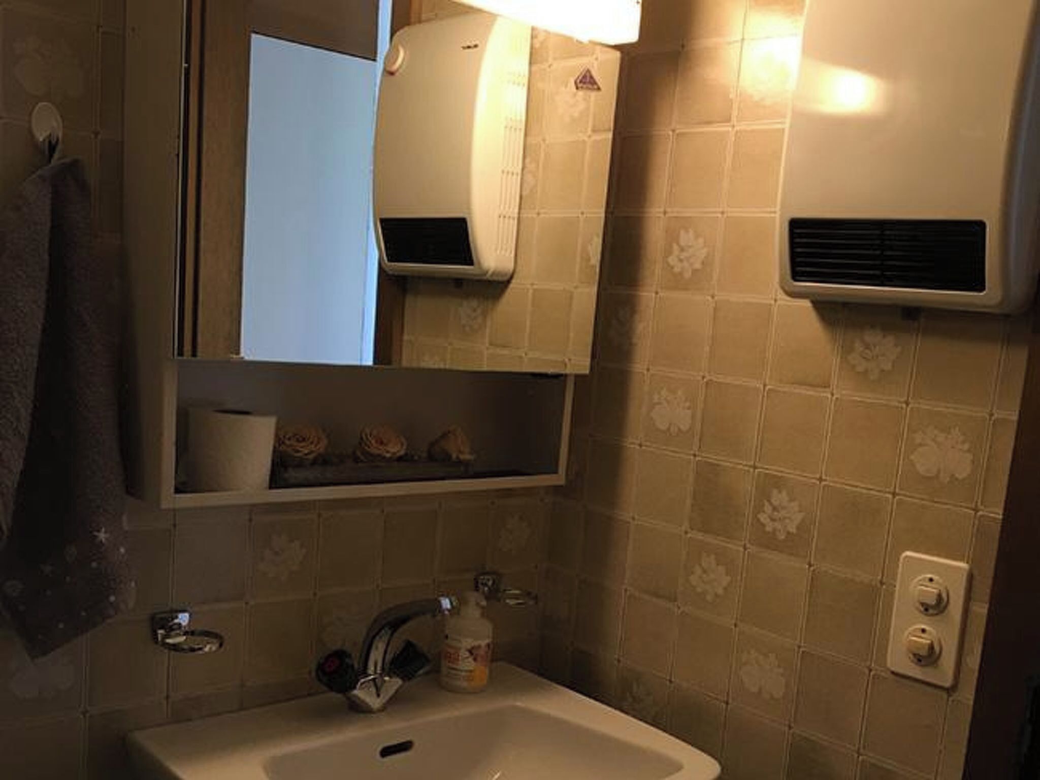 Un baño con lavabo, espejo, toallero y aire acondicionado de pared.