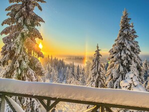 A snowy landscape with a sunrise, featuring snow-covered trees and a clear sky.