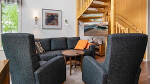 A modern living room with a gray sectional sofa, a round coffee table, and a wooden staircase. - Paltamon golfhovi a (sis. 2 golf pelioik by Interhome (Paltamo)