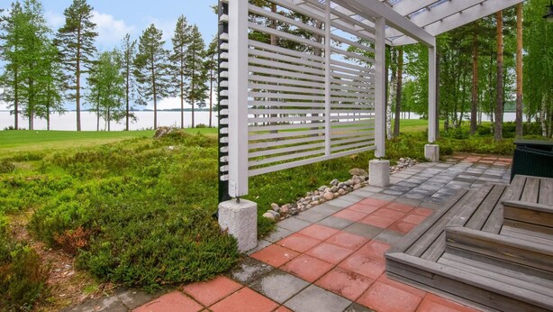 A covered outdoor area with a pergola, stone steps, and a view of a lake and trees. - Paltamon golfhovi a (sis. 2 golf pelioik by Interhome (Paltamo)