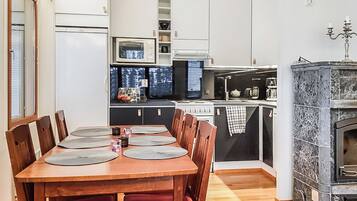 A compact kitchen with a dining area, featuring a wooden table with chairs, a built-in oven, and a black stove.