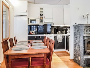 Une cuisine compacte avec un coin repas, comprenant une table en bois avec des chaises, un four encastré et une cuisinière noire.