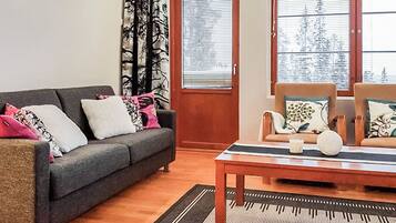 A living room with a grey sofa, a wooden coffee table, and two armchairs with patterned cushions.