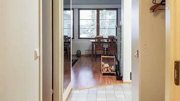 A hallway leading to a room with a wooden floor, a window, and a coat rack.