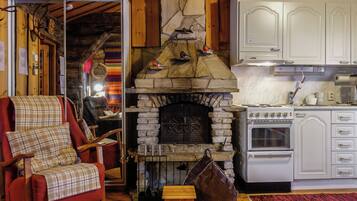 A cozy interior with a stone fireplace, a red armchair, and a kitchen area.