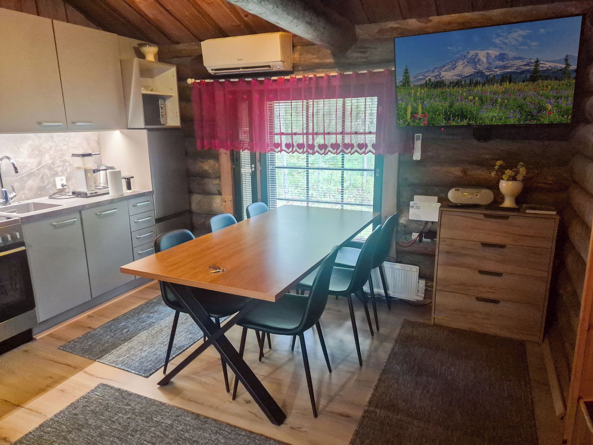 Une cuisine rustique avec une table à manger, des chaises et une vue sur un paysage montagneux.