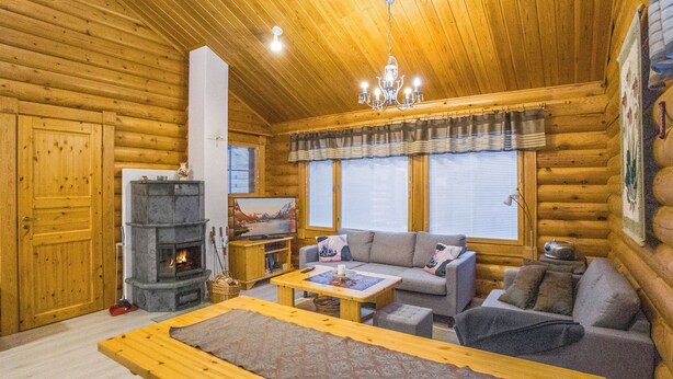 A cozy log cabin interior with a fireplace, wooden furniture, and a chandelier. - Kaukonraitti 4 c 2 by Interhome (Kuusamo)