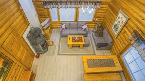 A cozy log cabin interior with a fireplace, a sofa set, a wooden coffee table, and a large window with curtains. - Kaukonraitti 4 c 2 by Interhome (Kuusamo)