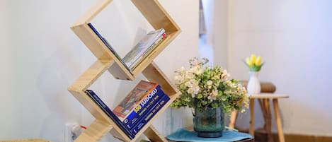 A wooden bookshelf with books and a vase of flowers.