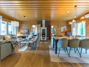 A log cabin interior with a fireplace, seating area, dining table, and large windows. - Lammassaari by Interhome (Ikaalinen)