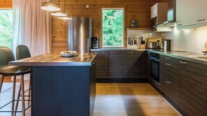Een moderne keuken met houten kastjes, een centraal eiland, barstoelen en een groot raam.