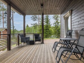 A covered outdoor deck with wooden flooring, metal railings, and outdoor furniture.