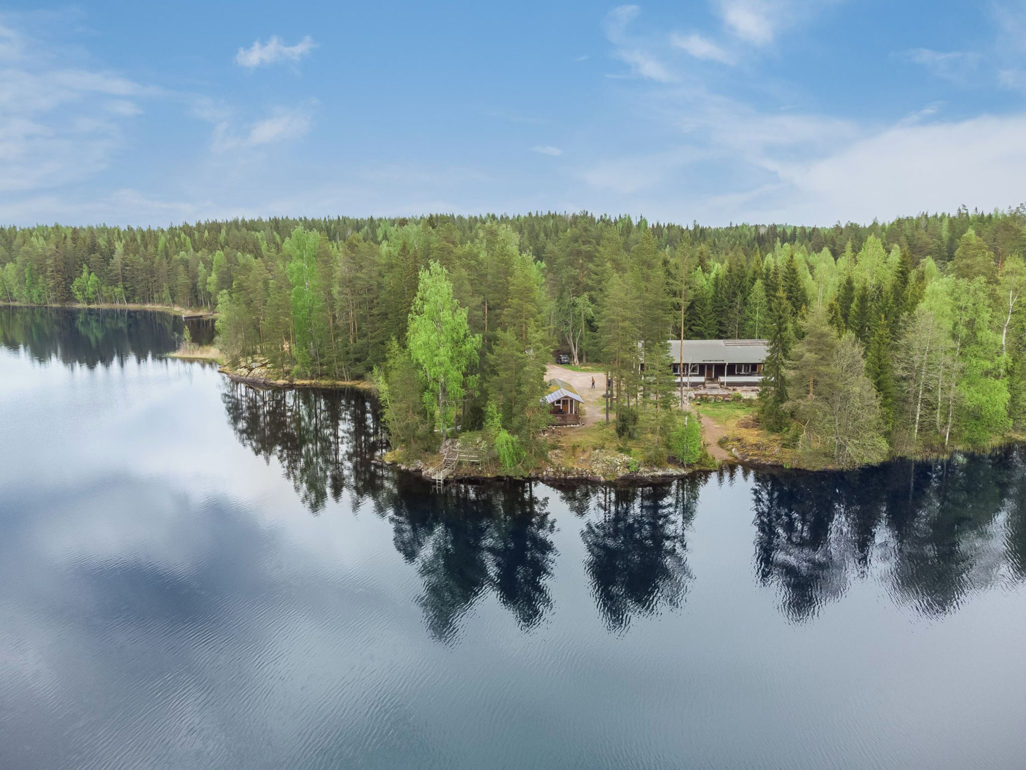 Un chalet au bord du lac, doté d’un quai, et entouré d’une forêt dense.