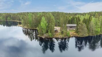 Un chalet au bord du lac, doté d’un quai, et entouré d’une forêt dense.