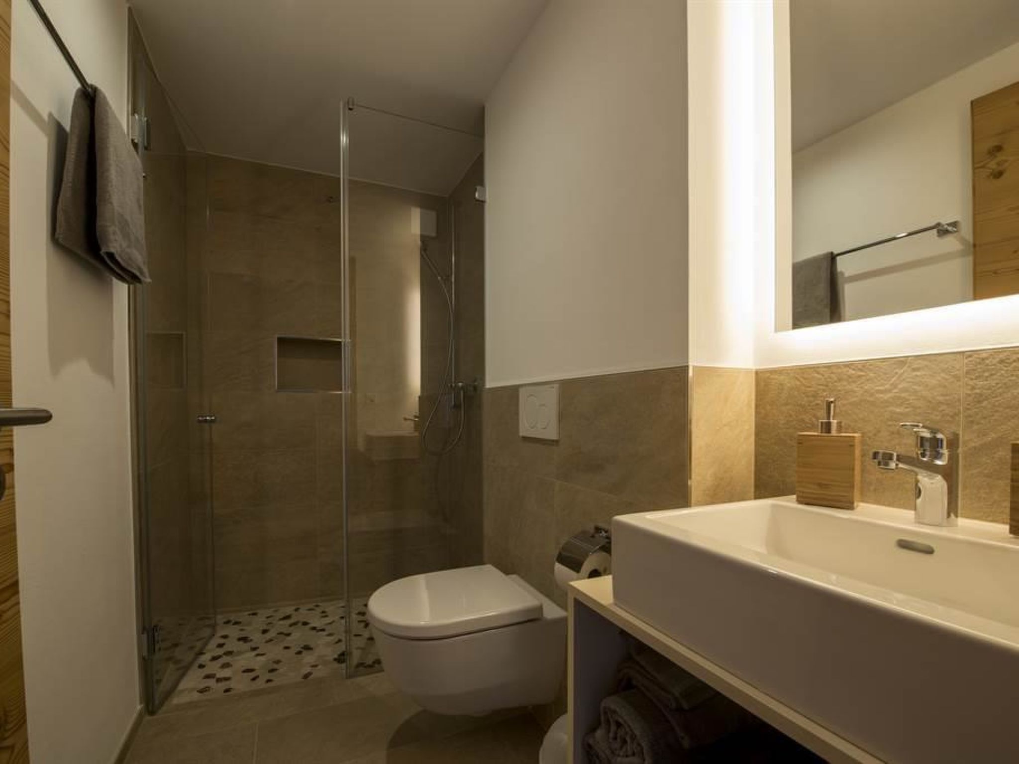 A modern bathroom with a glass-enclosed shower, a toilet, and a large sink with a mirror above it.
