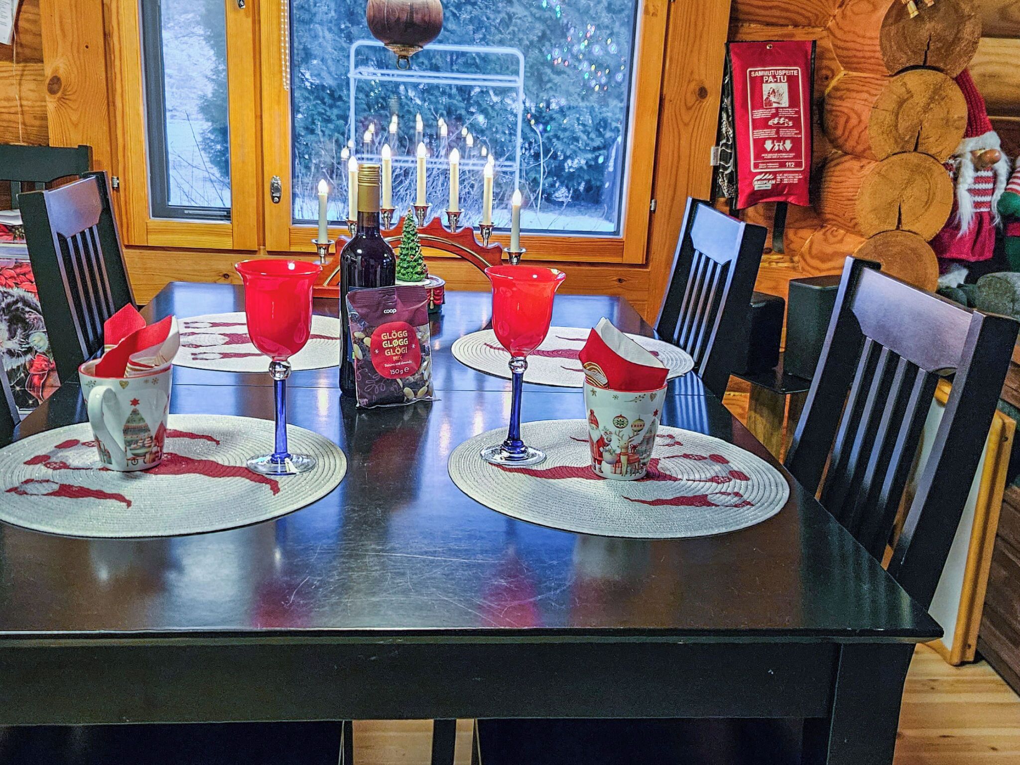 Una mesa de comedor dispuesta con servilletas rojas, una botella y una vela.