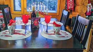 Una mesa de comedor dispuesta con servilletas rojas, una botella y una vela.