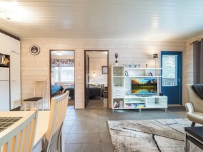 Un interior acogedor con comedor, sala de estar con televisor y un dormitorio visible a través de una puerta abierta.