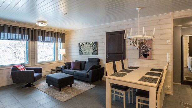 Ein modernes Wohnzimmer mit Sofa, Hocker und Esstisch.