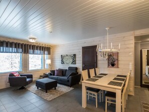 Uma sala moderna com sofá, banquinho e mesa de jantar.