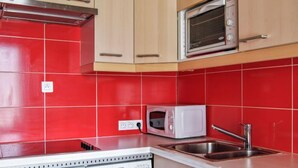 Una cucina con piastrelle rosse, un forno a microonde, una lavastoviglie e un lavello.
