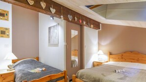 Una camera da letto con due letti di legno, una testiera in legno, un comodino con una lampada e una parete decorata con cuori.