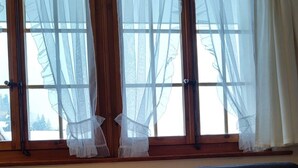Huoneessa on tummansininen sohva, oranssi koristetyyny, pieni pyöreä pöytä, jonka päällä palaa kynttilä, sekä patteri.