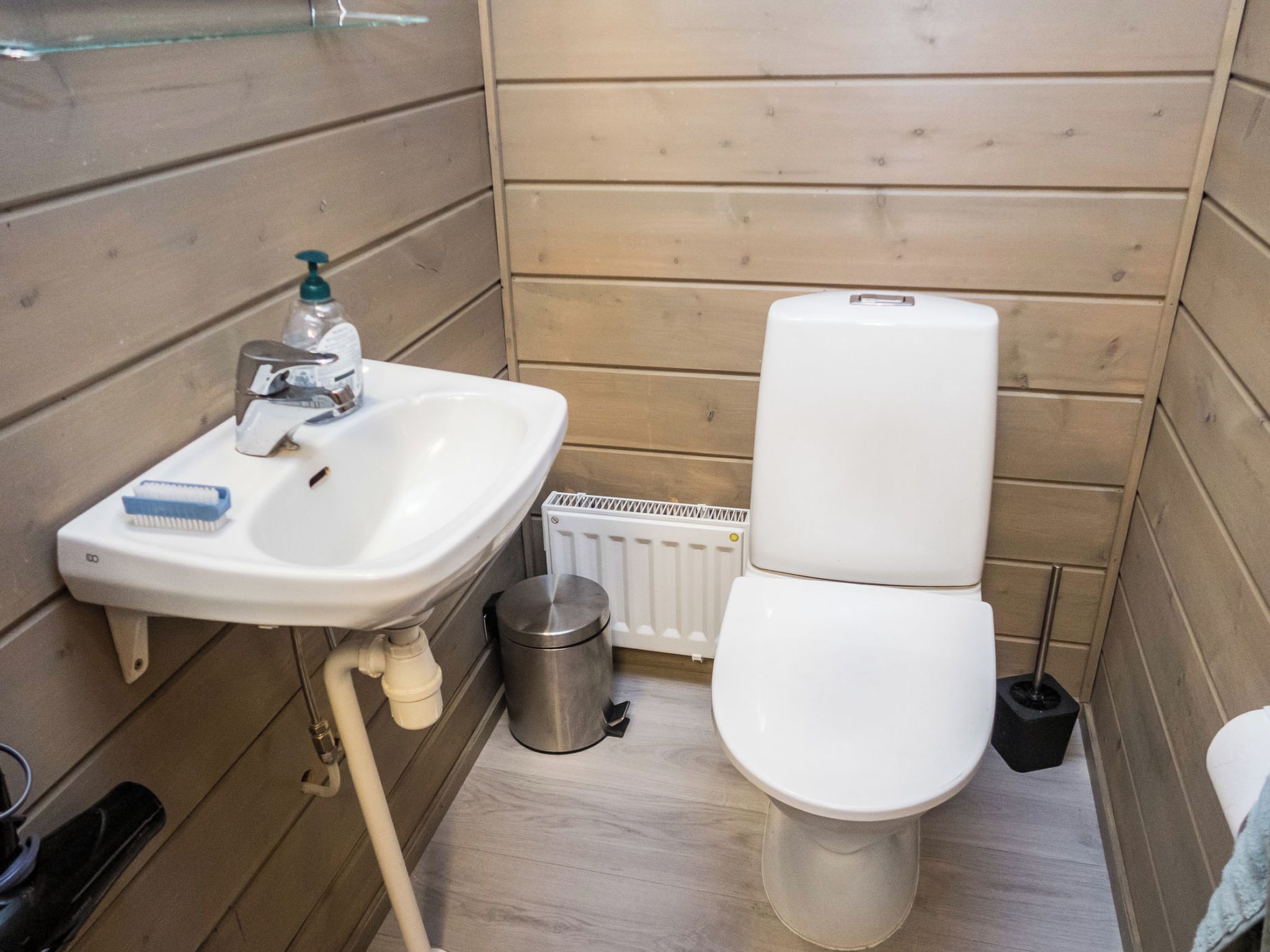 A compact bathroom with a white sink, toilet, and radiator.