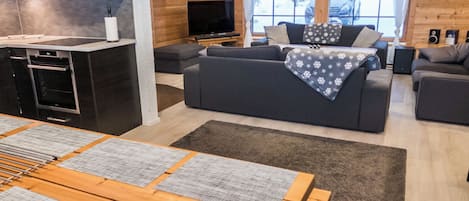 A modern living room with a sofa, a TV, and a dining area with a table and chairs.