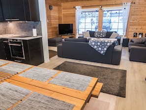 Una sala de estar moderna con sofá, televisor y comedor con mesa y sillas.