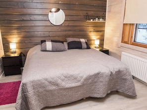 Quarto com cama, duas mesas de cabeceira, espelho, janela e radiador.